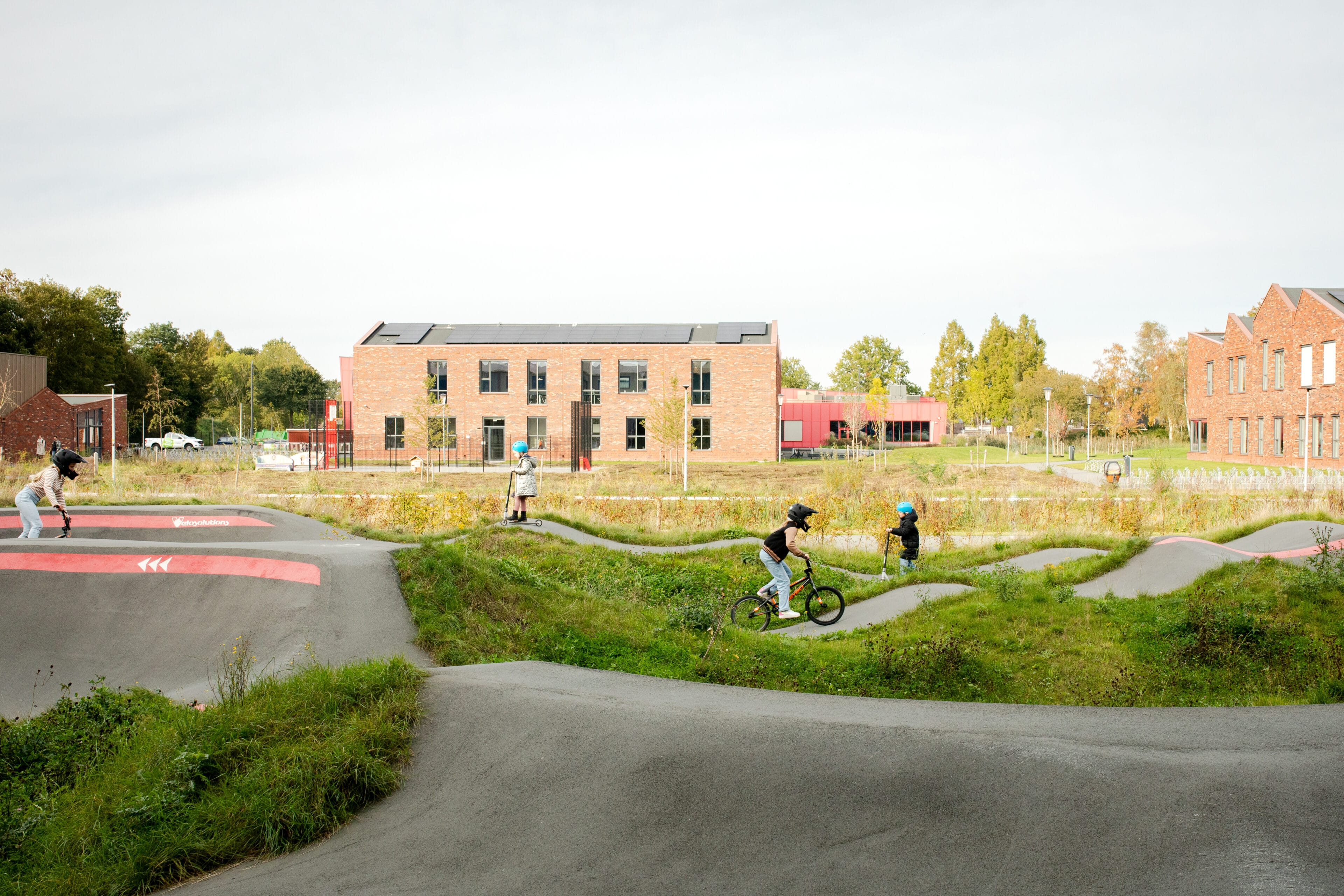 Kinderen op een skatebaan op fietsen en steppen