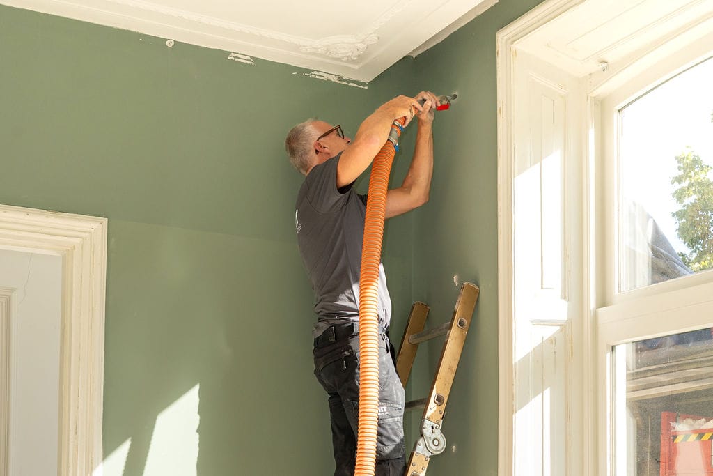 Werknemer isolatiebedrijf brengt isolatiemateriaal aan in muur