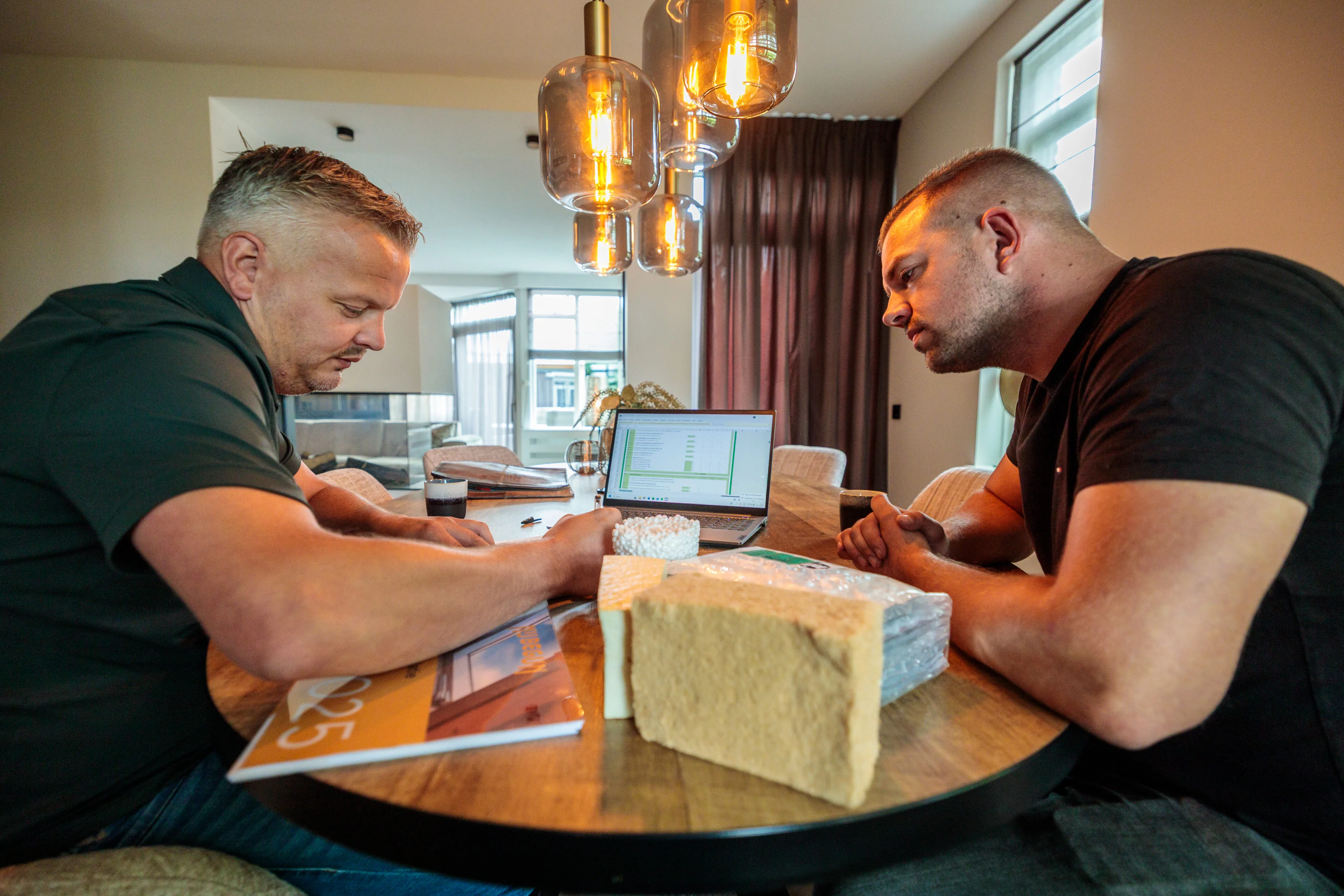 Isolatieadviseur adviseert woningeigenaar over isoleren tijdens gesprek aan keukentafel
