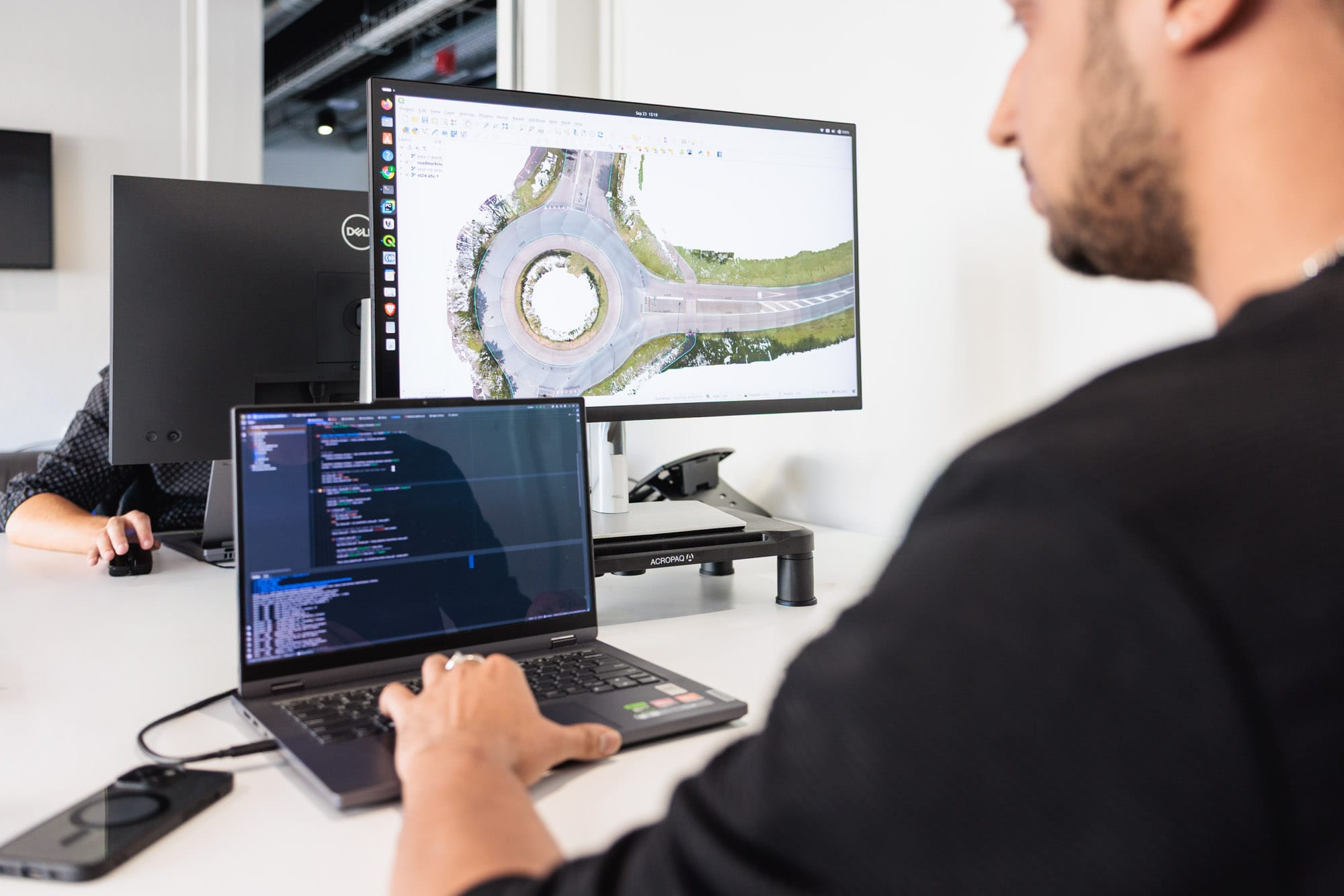 Man achter een beeldscherm en laptop