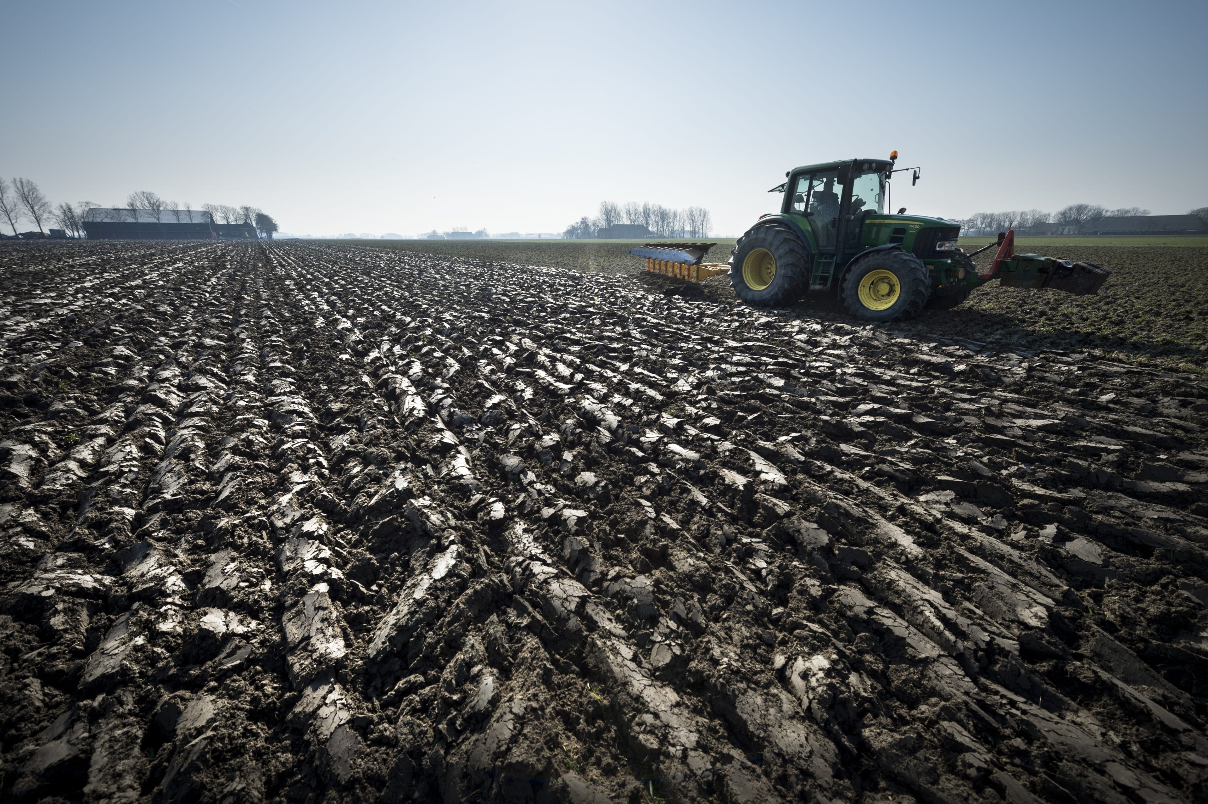 Een tractor met een ploeg in de Groningse klei