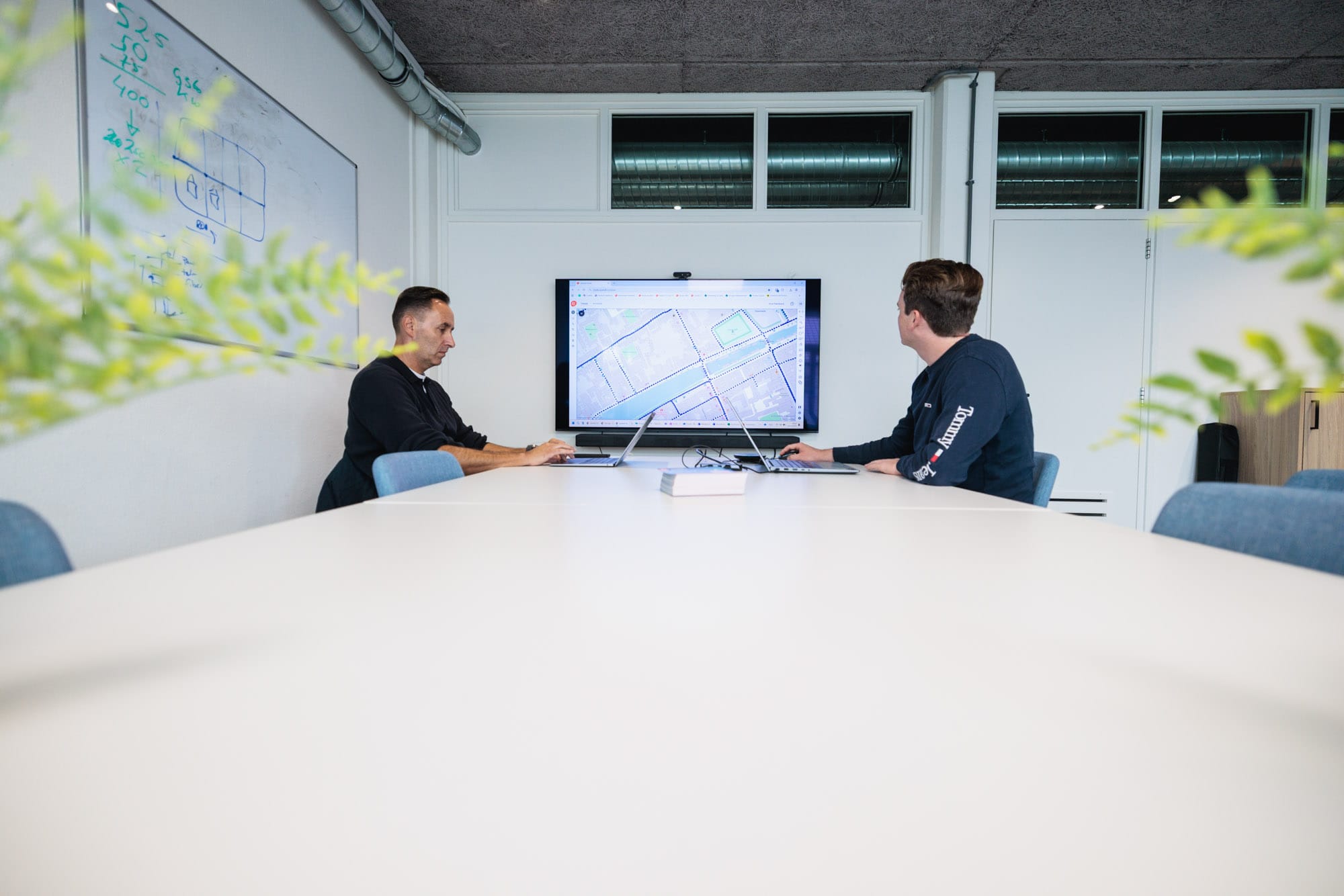 Twee mannen aan een tafel voor een beeldscherm