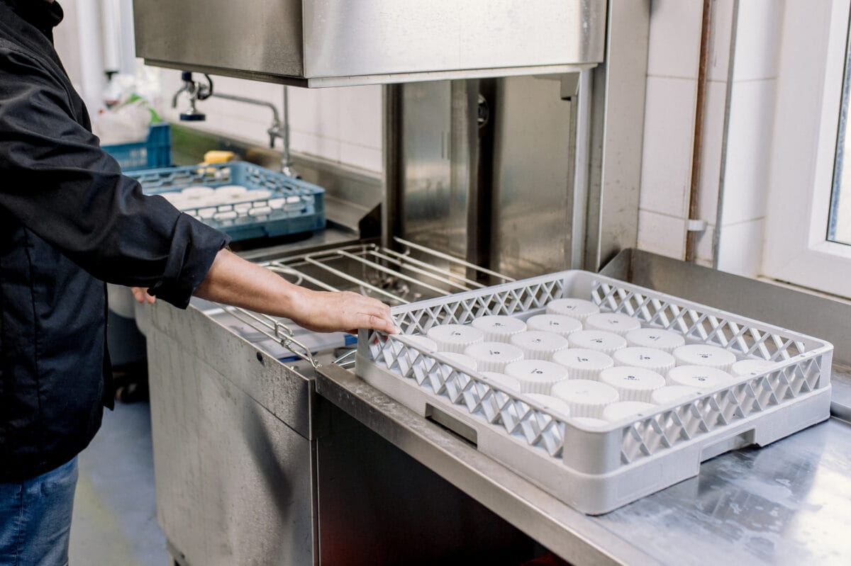 iemand die spullen in een professionele vaatwasser zet.