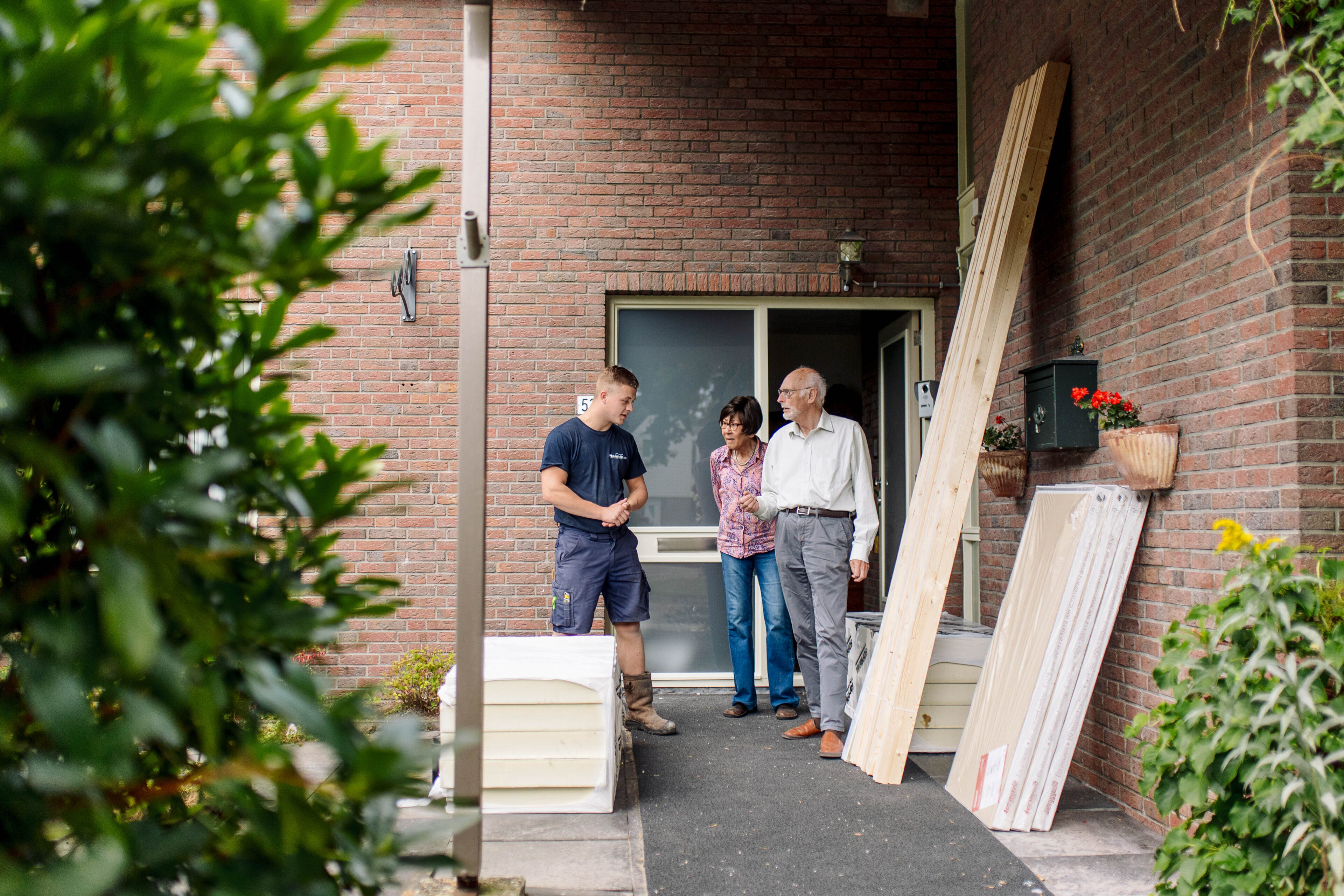 inwoners en medewerker isolatiebedrijf in gesprek met elkaar bij woning